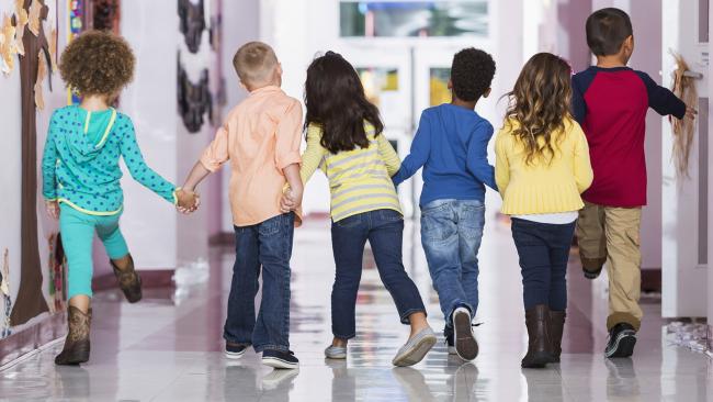 Preschoolers joyfully walking down a school hallway